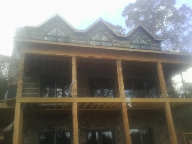 Dormers and porch framing on a large log home under construction — Roof Coating work by our crew in Houlton