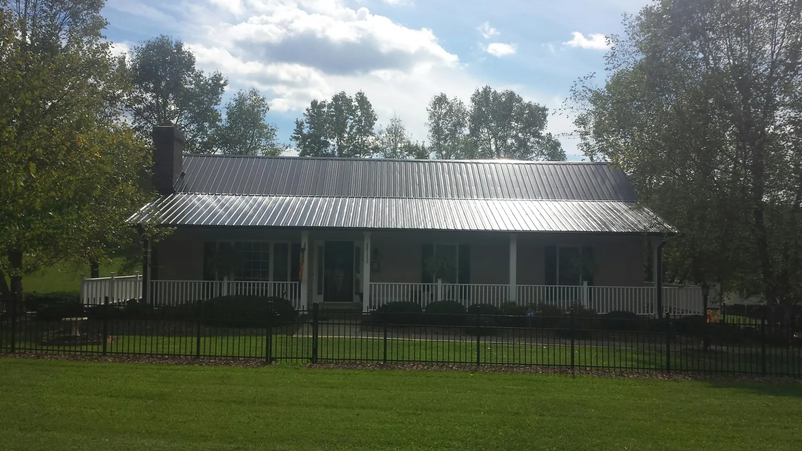 Gray metal roof on a brick ranch with a full width front porch — Gutter Guard Installation work by our crew in Houlton