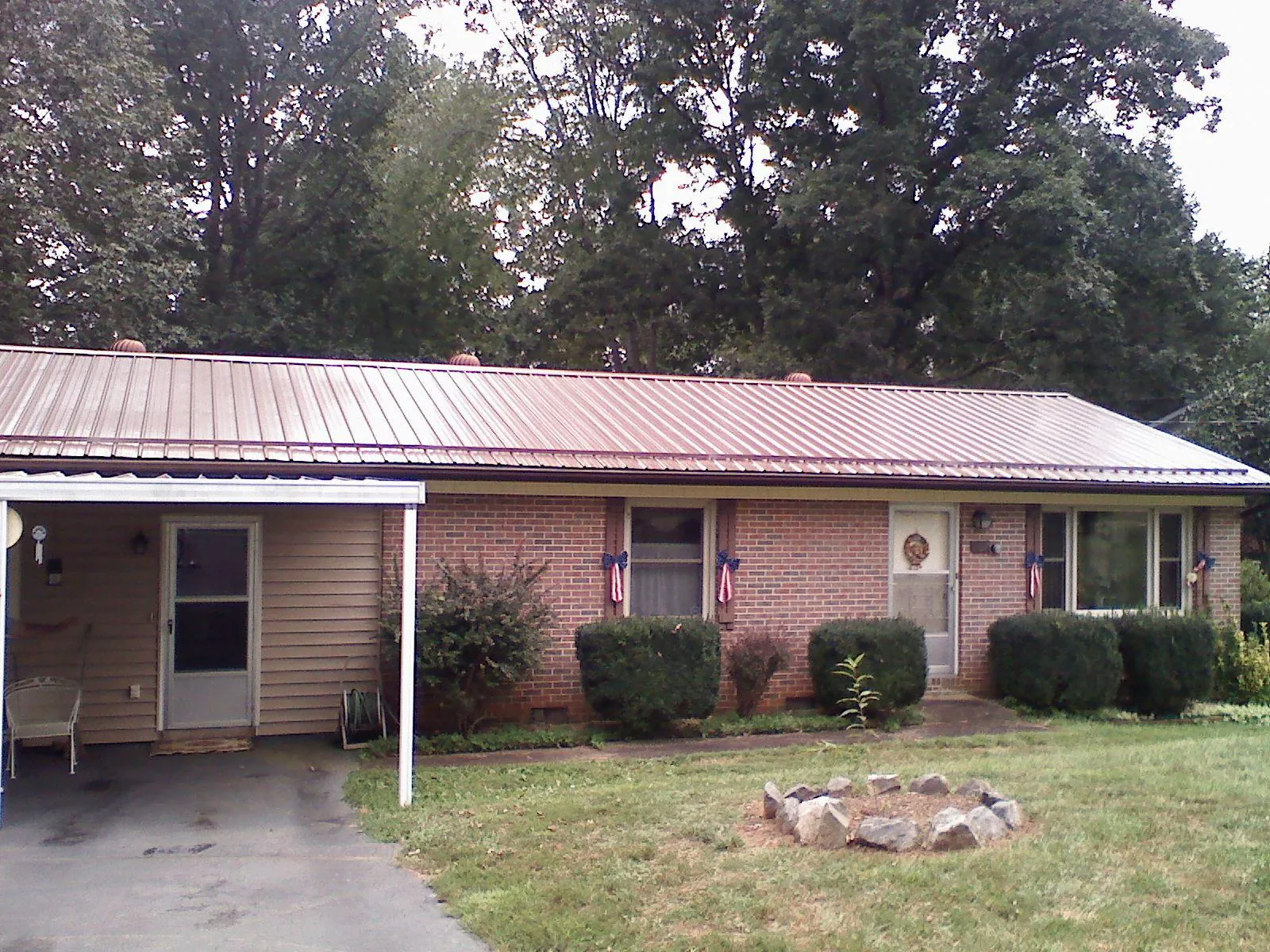 Bronze metal roof and carport on a brick ranch home — Roof Repair work by our crew in Houlton
